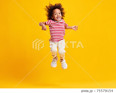 Active positive black kid jumping against blue background Active positive black kid jumping against blue background 75579154