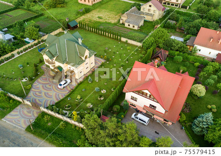 Aerial landscape of small town or village with rows of residential homes and green trees. Aerial landscape of small town or village with rows of residential homes and green trees. 75579415