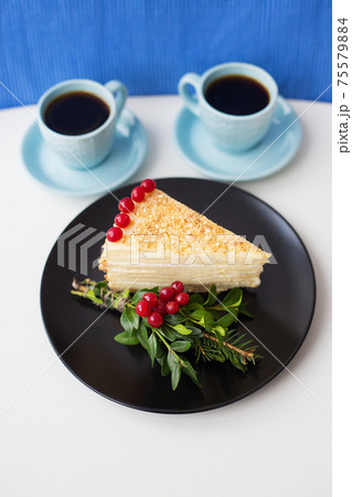 piece of cake decorated with tree branches and berries viburnum on a black plate 75579884