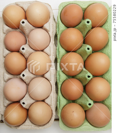 two paper trays for chicken eggs of different color filled with fresh eggs 75580229