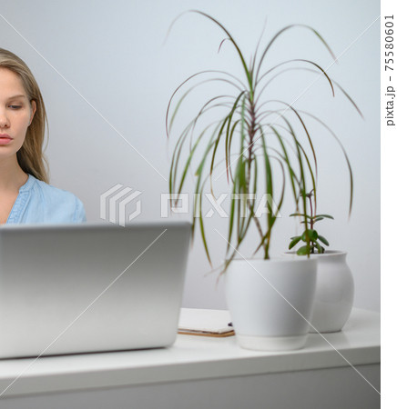 A girl with a laptop is studying at an online school. White room background 75580601