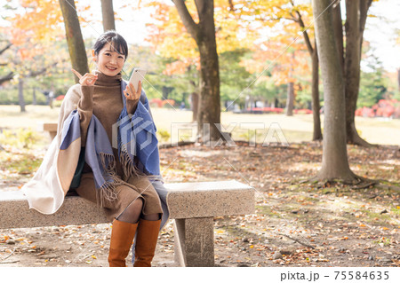 秋の公園でスマホを持った女性 秋の公園でスマホを持った女性 75584635
