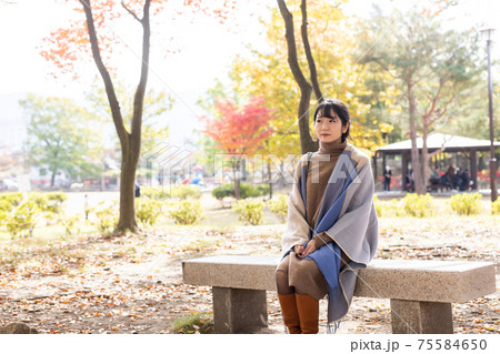 秋の公園にたたずむ女性 75584650