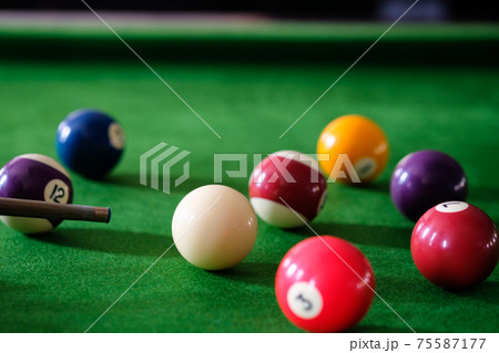 Man's hand and Cue arm playing snooker game or preparing aiming to shoot pool balls on a green billiard table. Colorful snooker balls on green frieze. Man's hand and Cue arm playing snooker game or preparing aiming to shoot pool balls on a green billiard table. Colorful snooker balls on green frieze. 75587177