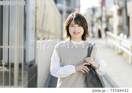バッグを肩にかけた若い女性　 75589432