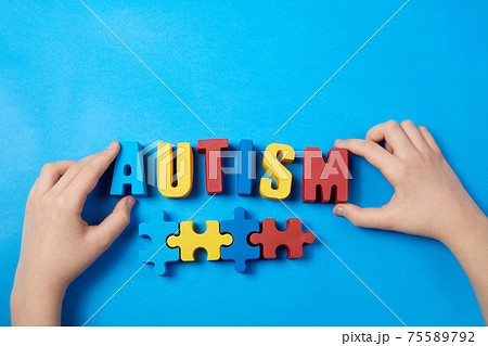 Autistic kid hands holding puzzle jigsaw and word autism, mental health concept. Autism spectrum, disorder. World autism awareness day. 75589792