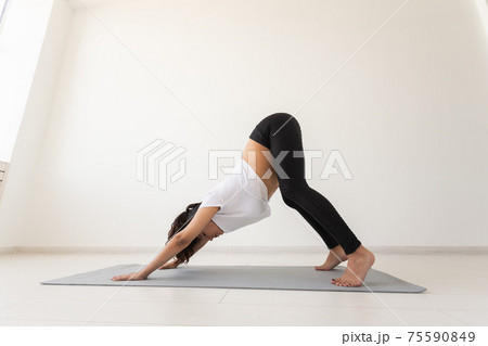 Purposeful pregnant woman exercises during yoga class and relaxes while sitting on a mat on the floor. Concept of physical and mental preparation of the body for childbirth. Place for text Purposeful pregnant woman exercises during yoga class and relaxes while sitting on a mat on the floor. Concept of physical and mental preparation of the body for childbirth. Place for text 75590849