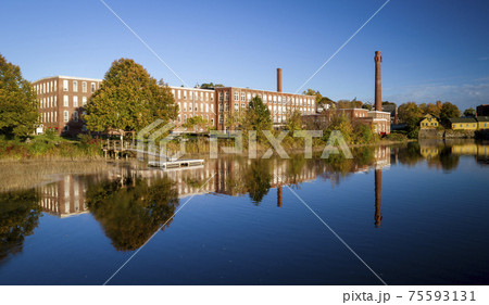 A 19th century textile mill has been renovated for modern use, seen reflected in the neighboring 75593131