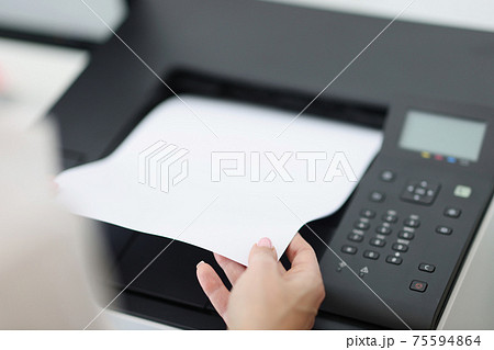 Person takes out white sheet from laser printer 75594864
