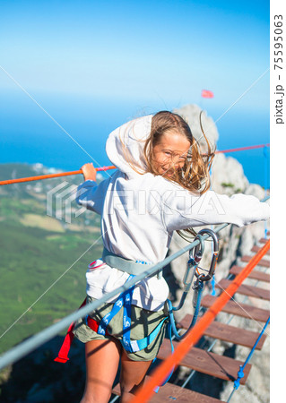 Girls crossing the chasm on the rope bridge. Girls crossing the chasm on the rope bridge. 75595063