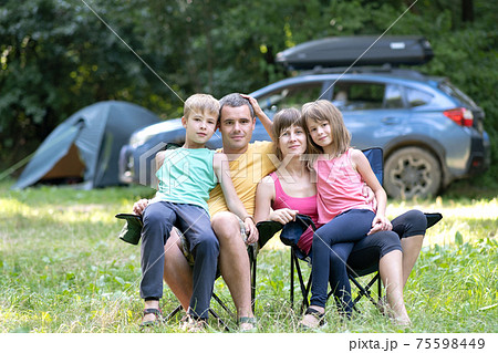 Happy young parents and their kids resting together at camping site in summer. Happy young parents and their kids resting together at camping site in summer. 75598449