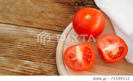 Whole and cut tomato on a wooden board for slicing. Rustic style and wood 75599312