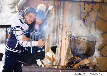 Family in love laughing and cooking in the winter outdoors. Bonfire, barbecue, bowler. Family in love laughing and cooking in the winter outdoors. Bonfire, barbecue, bowler. 75602476