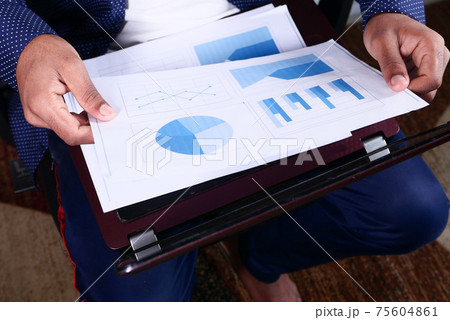 young man sitting on a chair with laptop analyzing financial data  75604861