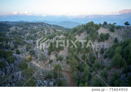 Aerial view of rocky mountains with evergreen trees. Aerial view of rocky mountains with evergreen trees. 75604950