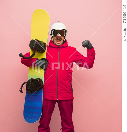 Male snowboarder with skiing gear in bright ski suit isolated on pink background Male snowboarder with skiing gear in bright ski suit isolated on pink background 75606414