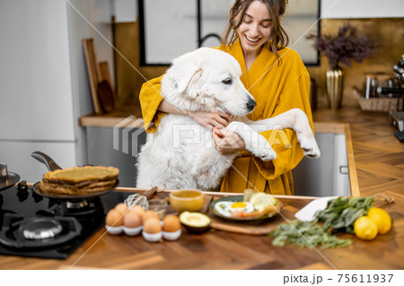 Woman with dog on the kitchen in the morning Woman with dog on the kitchen in the morning 75611937