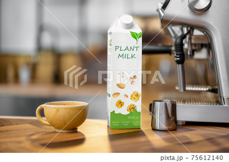 Packaging of vegetable milk near a cup of coffee 75612140
