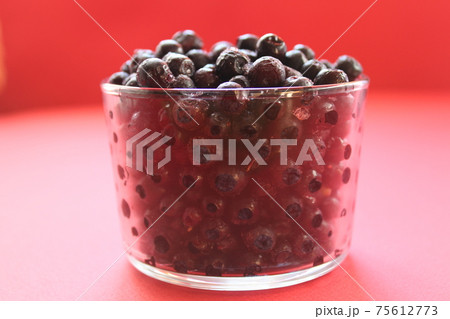 berry still life blueberries or currants in a glass on a red background with a place for text and a copyspace view from the side 75612773