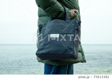 Woman in winter clothing with stylish eco bag on sea shore 75613382