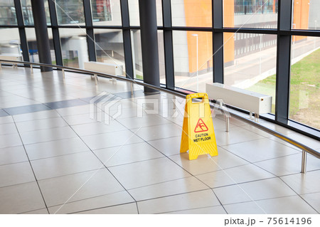 Cleaning service indoors. Yellow plastic caution sign - beware slippery on the floor at airport or shopping mall hall 75614196