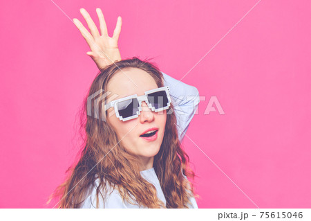 Stylish caucasian girl in a pale blue t-shirt and 8-bit glasses. Screaming at the camera and portray the queen. Toned. Stylish caucasian girl in a pale blue t-shirt and 8-bit glasses. Screaming at the camera and portray the queen. Toned. 75615046
