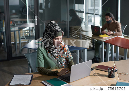 Muslim woman typing on laptop at office Muslim woman typing on laptop at office 75615705