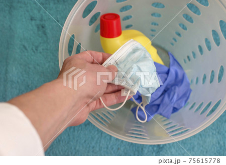 Man hands throwing medical masks, gloves and disinfectant bottle in the trash, end of quarantine and disease coronavirus COVID-19 concept. Selective focus 75615778