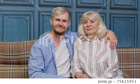Family of senior mother and handsome adult son or grandson looking at camera, domestic weekends 75615951