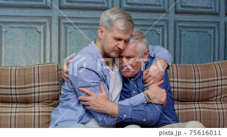 Adult man son hugging and consoling sadness old age father with love, mental health, social problems 75616011