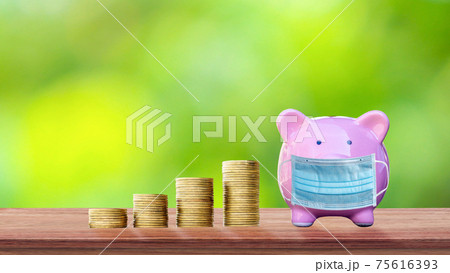 Coins and piggy banks wear anti-virus masks on wooden tables and blurred green background as ideas for spending money during the virus outbreak. Coins and piggy banks wear anti-virus masks on wooden tables and blurred green background as ideas for spending money during the virus outbreak. 75616393