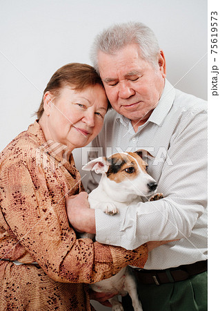 An elderly couple with a dog on a white background.  75619573