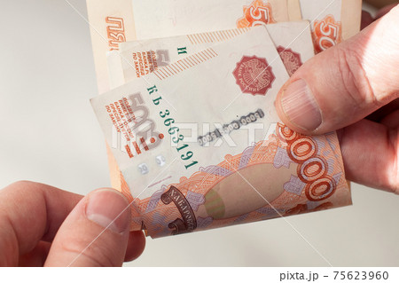 Man giving money five thousand ruble bills to his partner. Man giving money five thousand ruble bills to his partner. 75623960