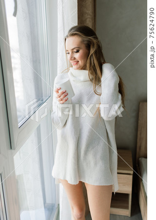 Attractive female with cup of coffee, smartphone and cakes in the bed Attractive female with cup of coffee, smartphone and cakes in the bed 75624790