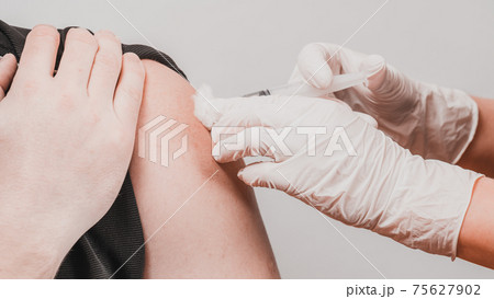 Vaccination close up, injection of vaccine in hand, doctor in white gloves. 75627902