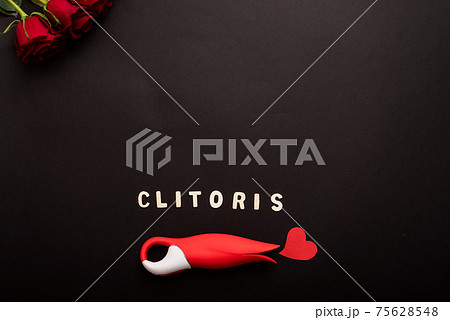 Top view of roses, clitoral vibrator in the form of a red tulip, heart and the inscription clitoris on a black background. Flat lay. Copy space Top view of roses, clitoral vibrator in the form of a red tulip, heart and the inscription clitoris on a black background. Flat lay. Copy space 75628548