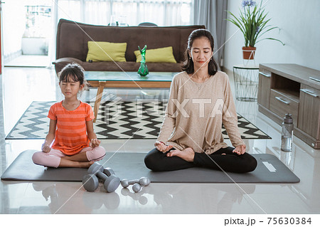 mother doing yoga exercise at at home with her daughter together 75630384