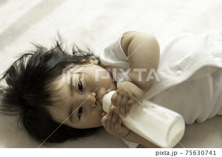 自分で哺乳瓶を持って ミルクを飲む赤ちゃん 0歳 生後8か月 日本人 女の子 の写真素材