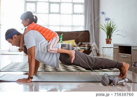 father and daugther exercising together at home 75630760