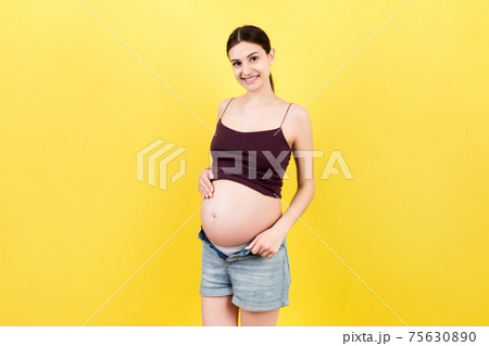 pregnant woman in unzipped jeans showing her naked belly at colorful background with copy space. Baby expecting concept pregnant woman in unzipped jeans showing her naked belly at colorful background with copy space. Baby expecting concept 75630890