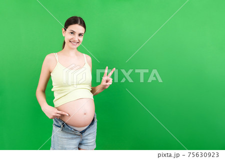 Young beautiful teenager girl pregnant expecting baby over isolated colored background smiling showing big belly 75630923