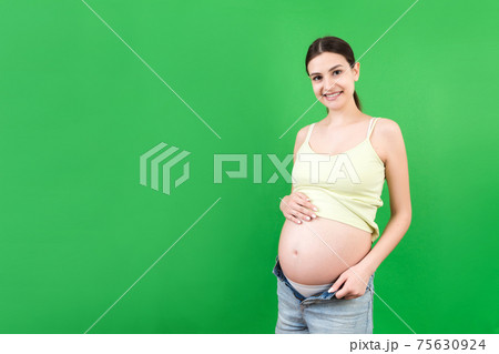 pregnant woman in unzipped jeans showing her baby bump at colorful background with copy space. Waiting for a baby concept pregnant woman in unzipped jeans showing her baby bump at colorful background with copy space. Waiting for a baby concept 75630924