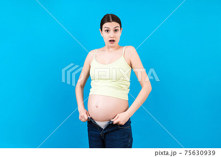 pregnant woman in unzipped jeans showing her naked belly at colorful background with copy space. Baby expecting concept pregnant woman in unzipped jeans showing her naked belly at colorful background with copy space. Baby expecting concept 75630939