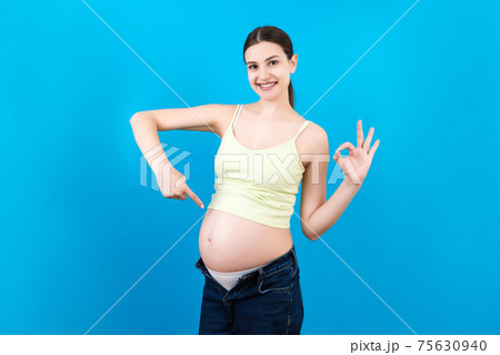 Young beautiful teenager girl pregnant expecting baby over isolated colored background smiling showing big belly Young beautiful teenager girl pregnant expecting baby over isolated colored background smiling showing big belly 75630940