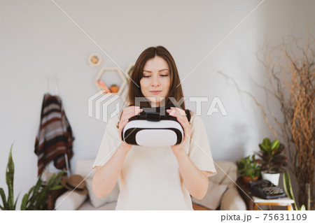 The person is holding a virtual reality headset and looks into it. Cyberspace in a small laptop The person is holding a virtual reality headset and looks into it. Cyberspace in a small laptop 75631109