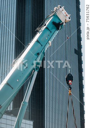 blue crane lifting mechanism with hooks near the glass modern building, crane and hydraulic high lift up to 120 meters 75631762