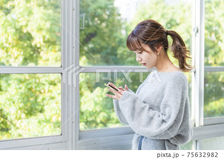 スマホ 窓際の女性 ビジネスシーン スマホ 窓際の女性 ビジネスシーン 75632982
