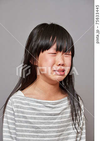 スタジオ撮影した可愛い小学生の女の子の泣いている表情の写真素材