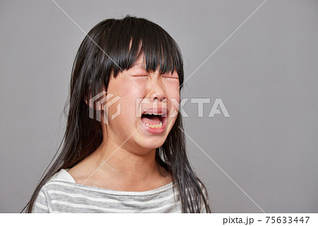 スタジオ撮影した可愛い小学生の女の子の泣いている表情の写真素材