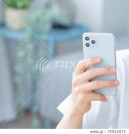 リビングでスマホを操作する若い男性の手元のアップ 正方形 リビングでスマホを操作する若い男性の手元のアップ 正方形 75633873